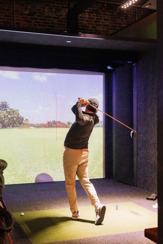 golfer practicing using indoor golf simulator